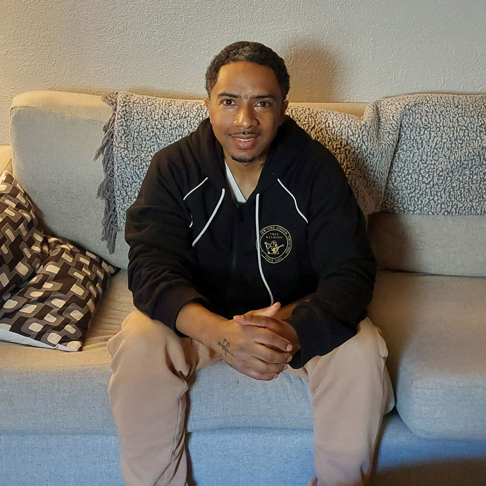 Community Support Network client sitting on a couch smiling for the camera