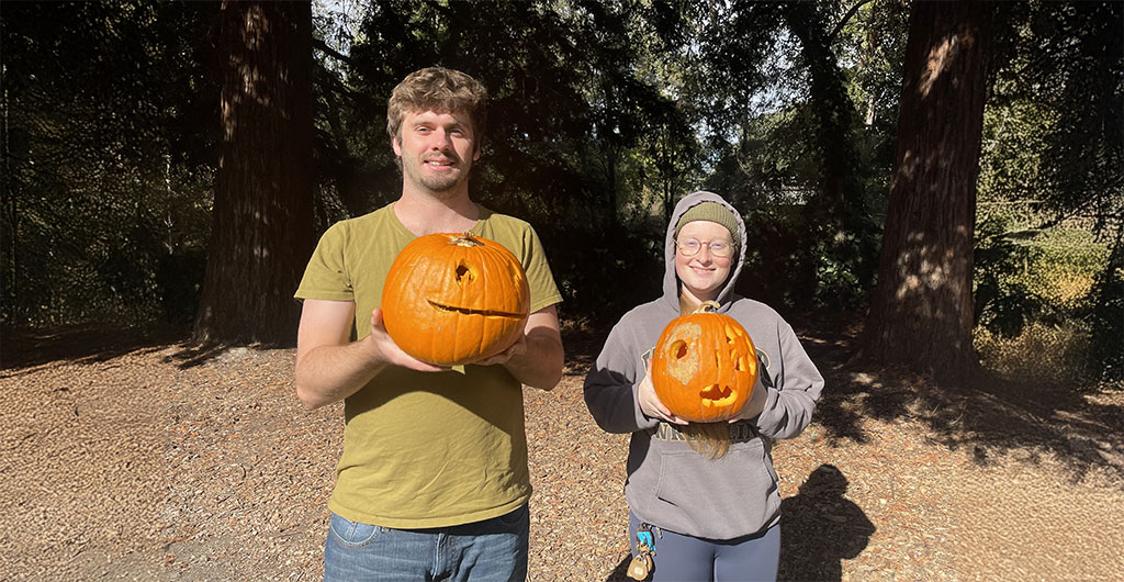 Two people smiling and holding their carved pumpkins